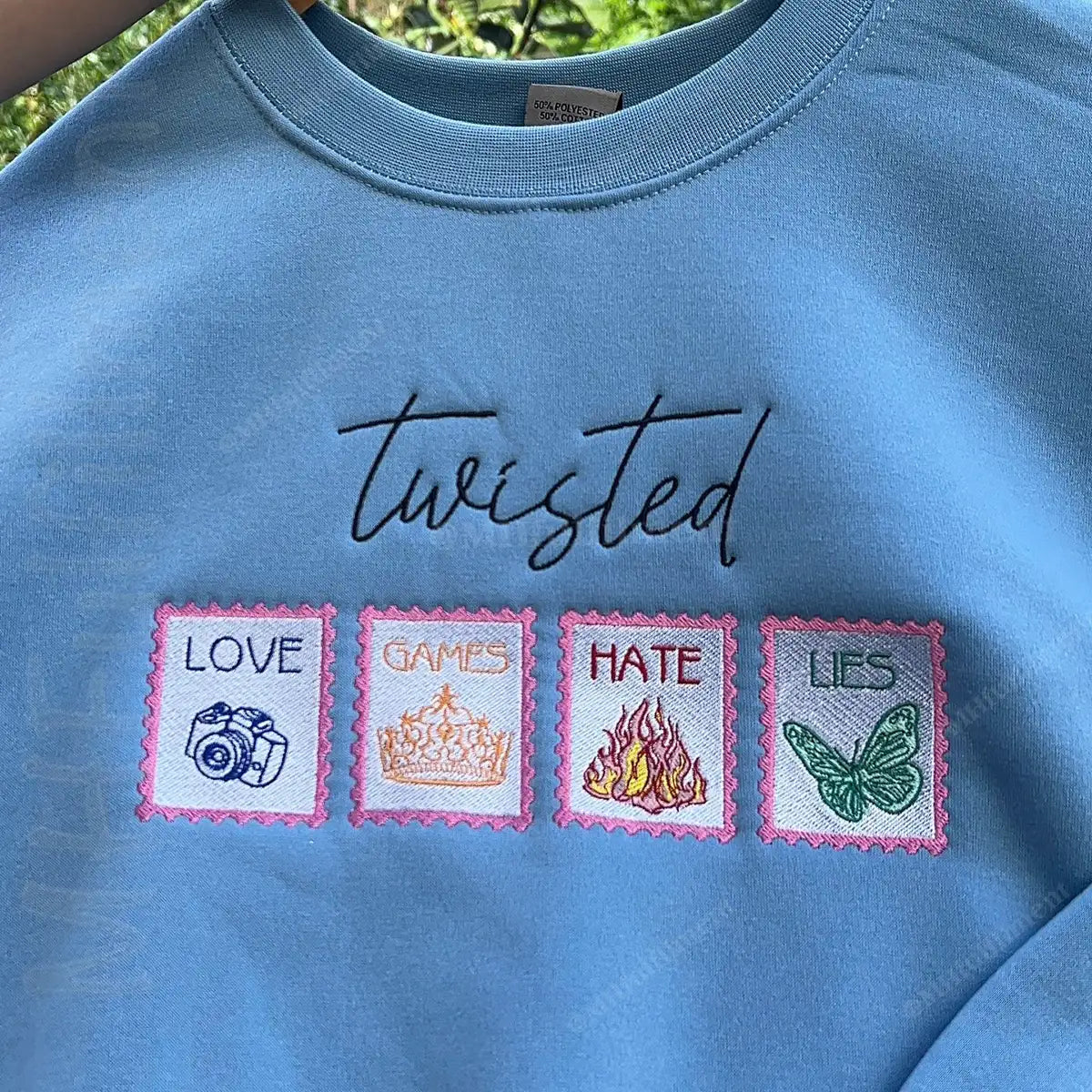 Blue sweatshirt with embroidered text and symbols on a green background