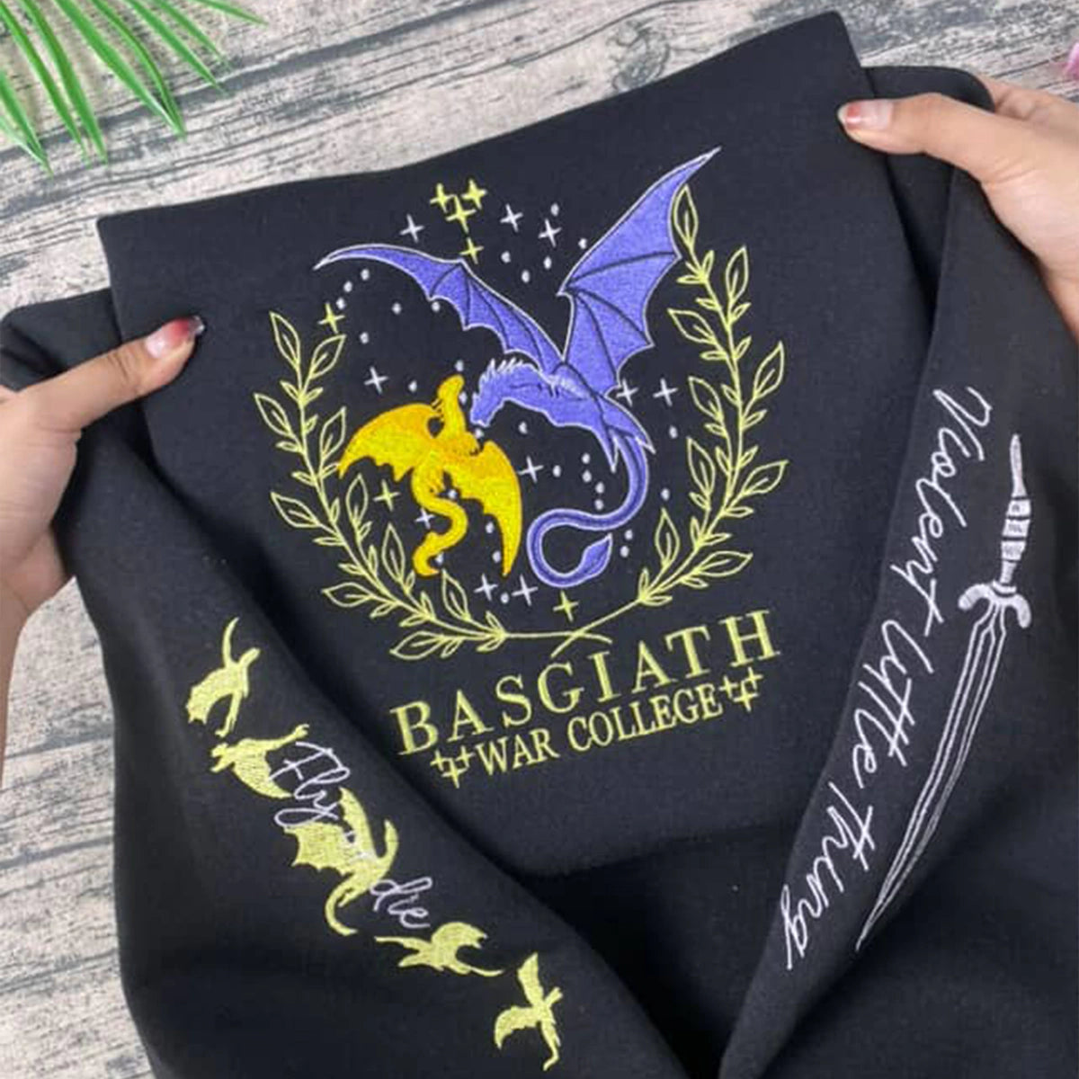 Black fabric with embroidered dragon design and text on a wooden surface