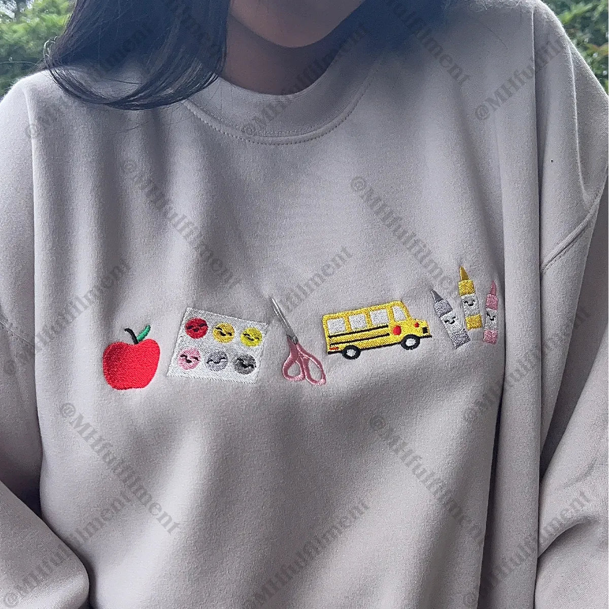 Gray sweatshirt with various embroidered items including an apple, school bus, and scissors.