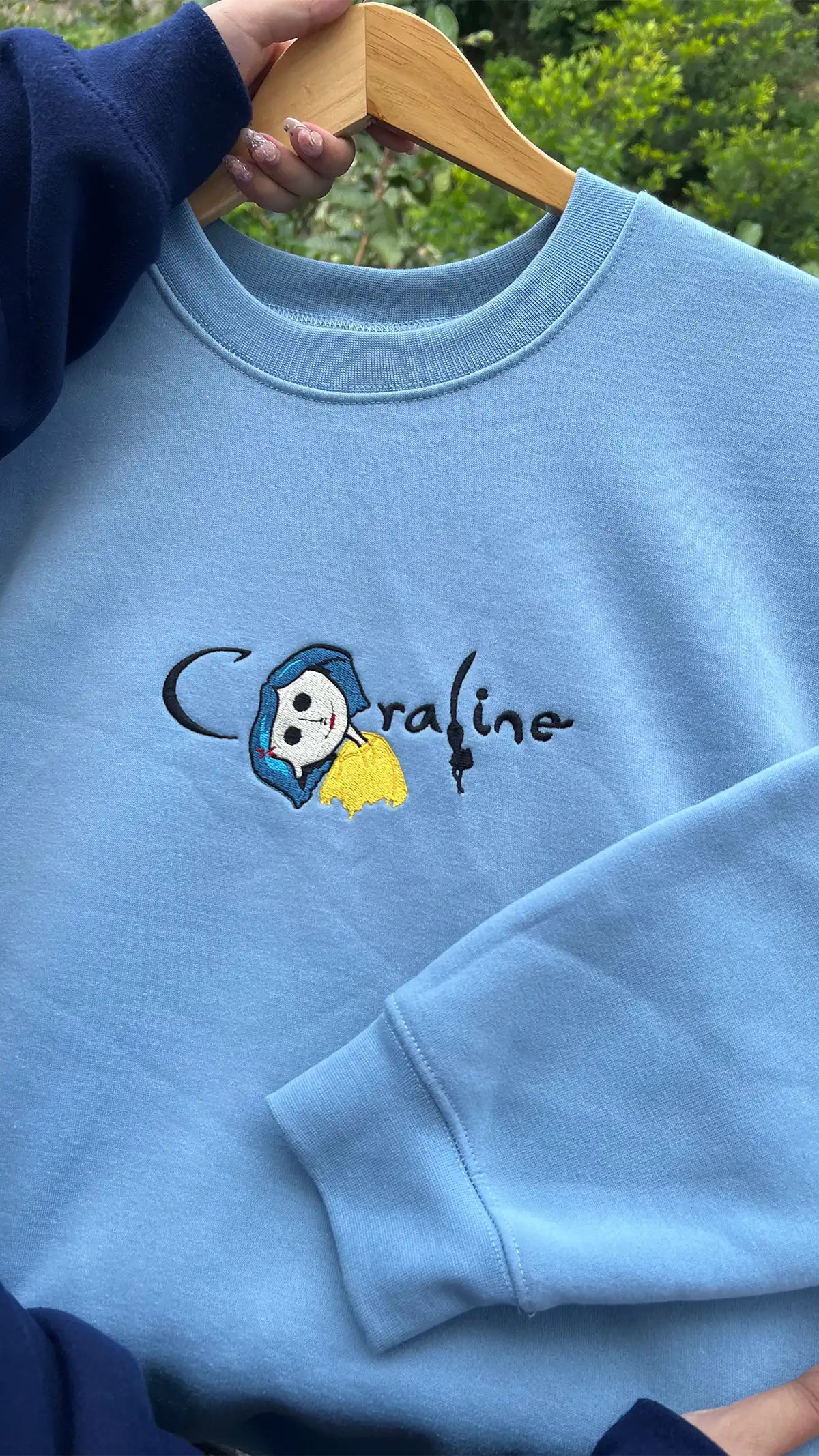 Couple wearing Coraline embroidered crewnecks