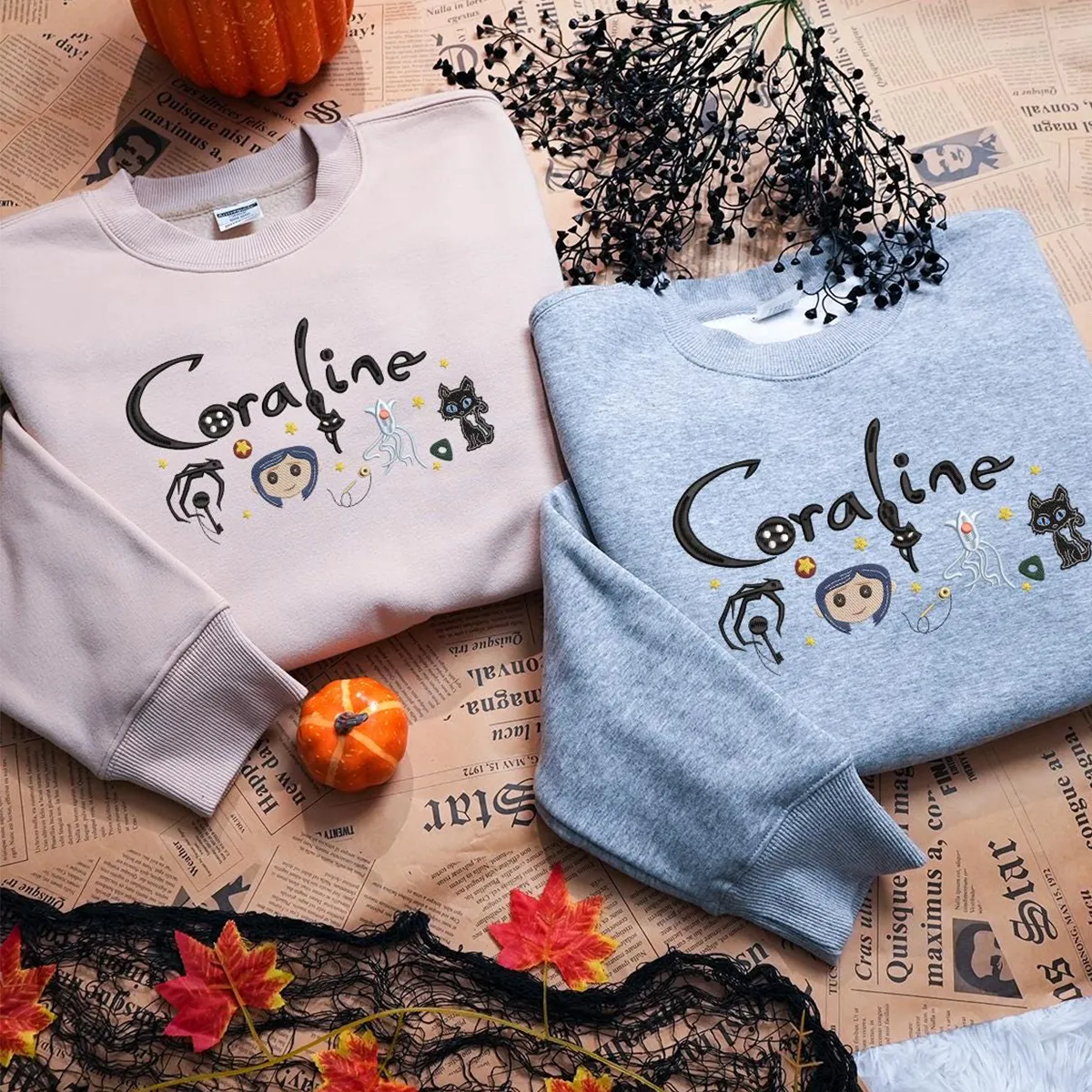Two sweaters with 'Coraline' design on a newspaper background with pumpkins and leaves.