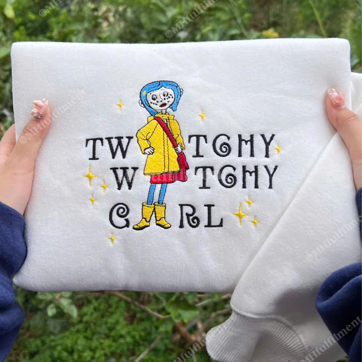 Embroidered design on a white fabric with text and a character in a yellow raincoat.