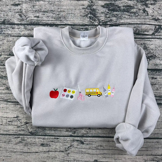 Gray sweatshirt with various emojis on a wooden surface