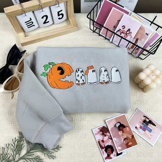 Gray sweatshirt with Halloween-themed design on a surface with decorative items.