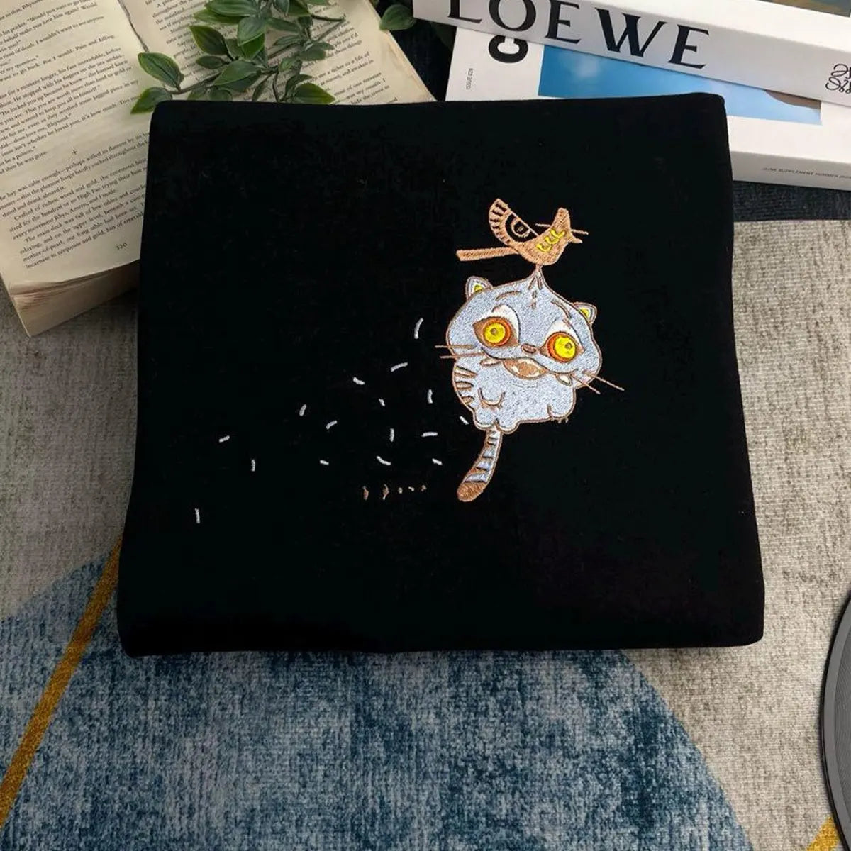 Black pouch with a cat and bird design on a textured surface