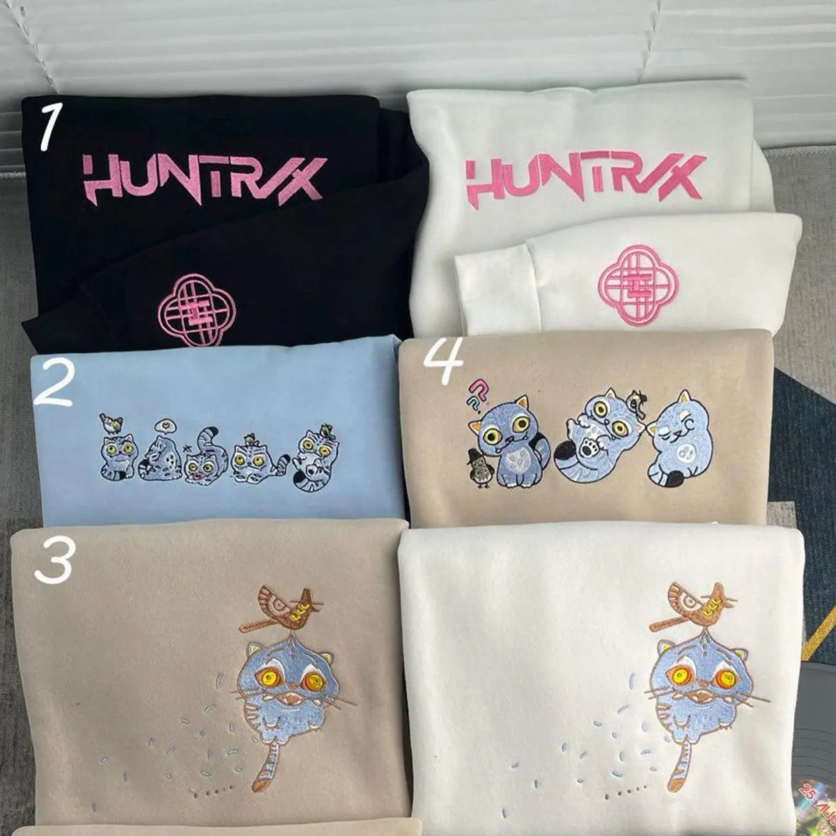 Collection of folded clothing with 'HUNTRX' branding and cartoon designs.