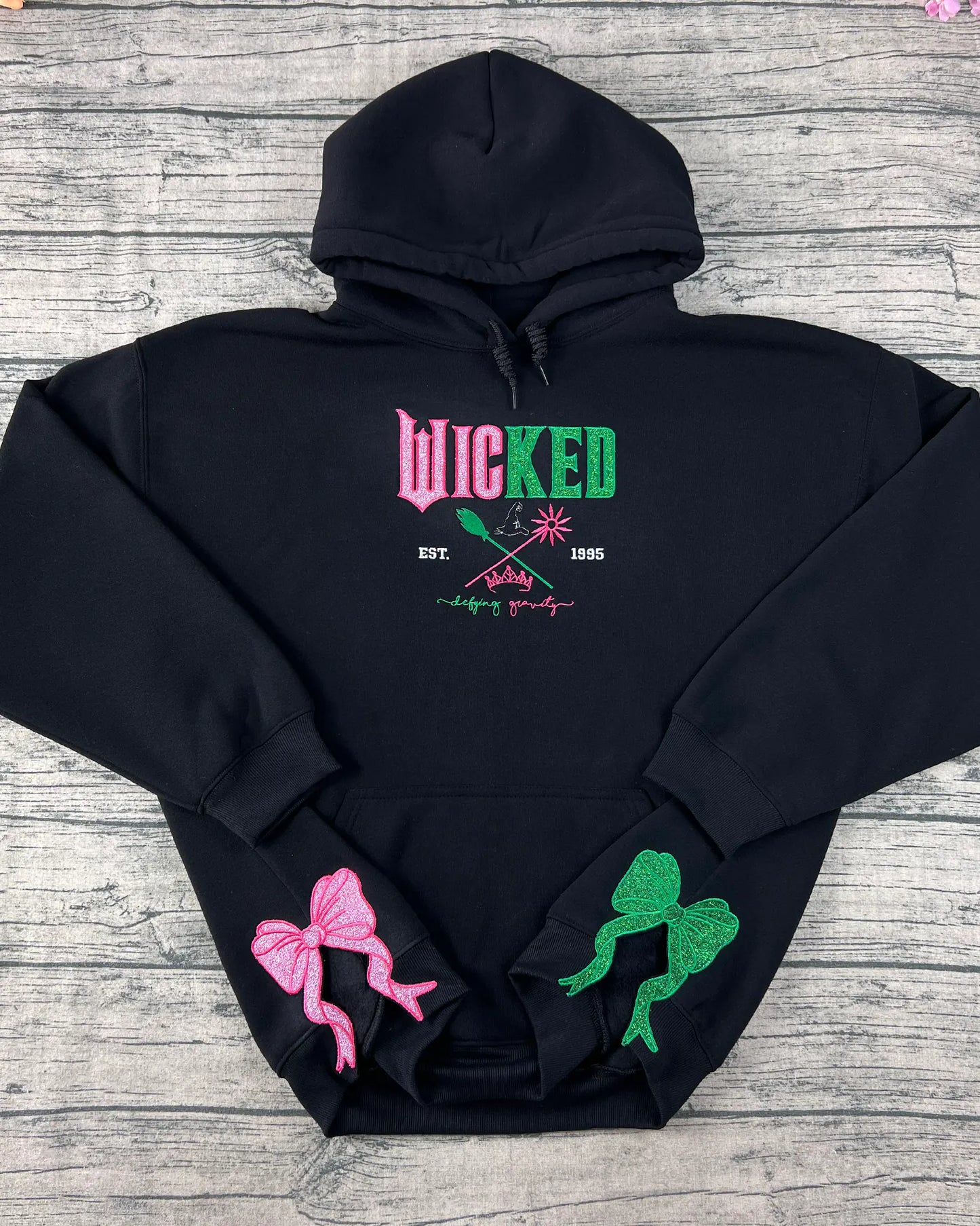 Embroidered Wicked sweatshirt hoodie featuring Defy Gravity applique with Glinda and Elphaba design. Perfect Halloween witch gift for her and Wizard of Oz fans.
