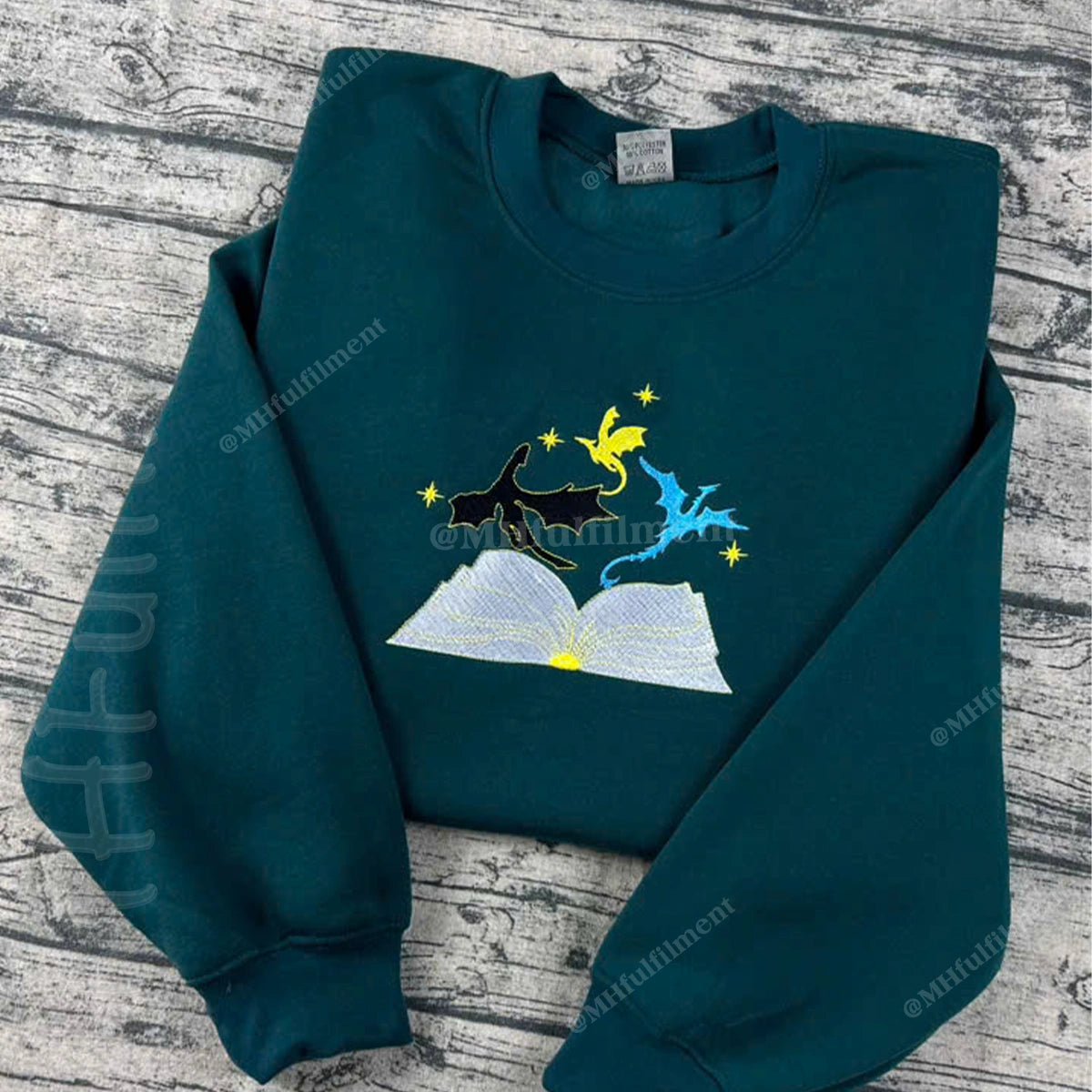 Folded teal sweatshirt with a graphic design on a wooden surface
