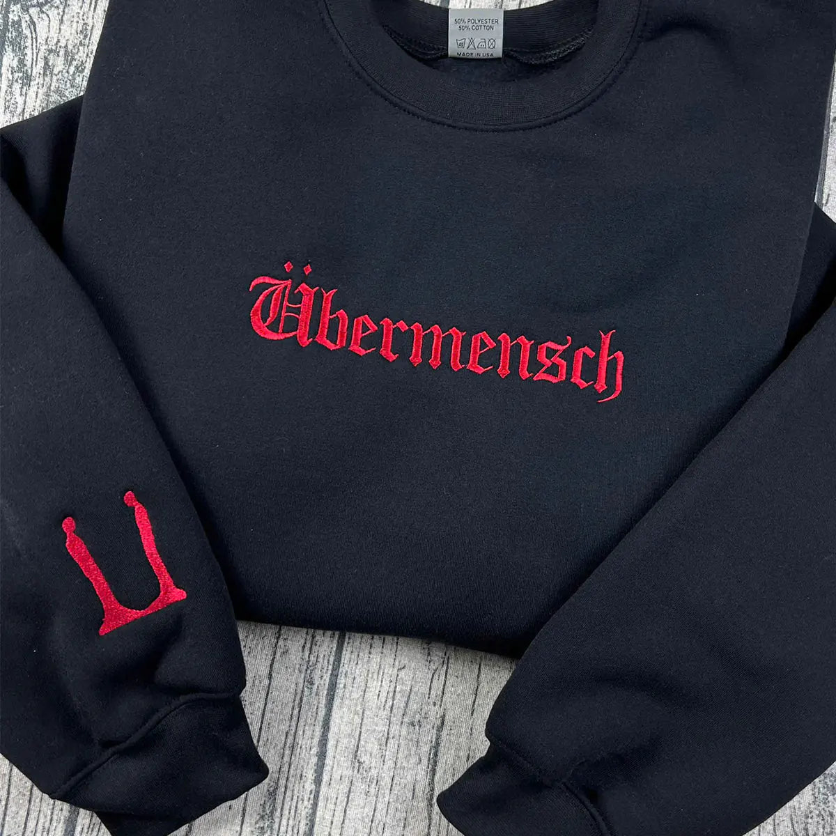 Black sweatshirt with red 'Ubermensch' text on a wooden surface