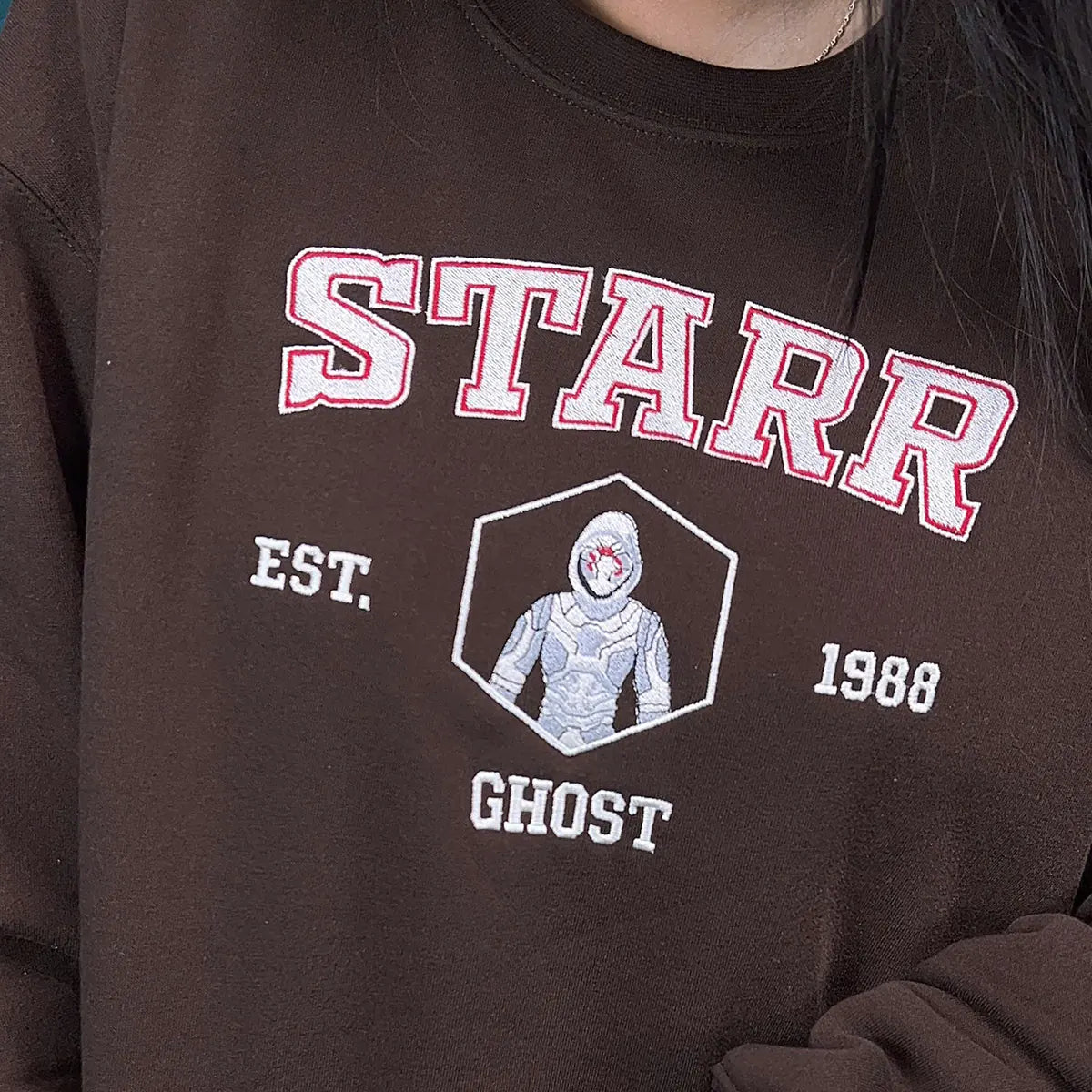 Brown sweatshirt with 'STARR' and 'GHOST' design on a person wearing it.