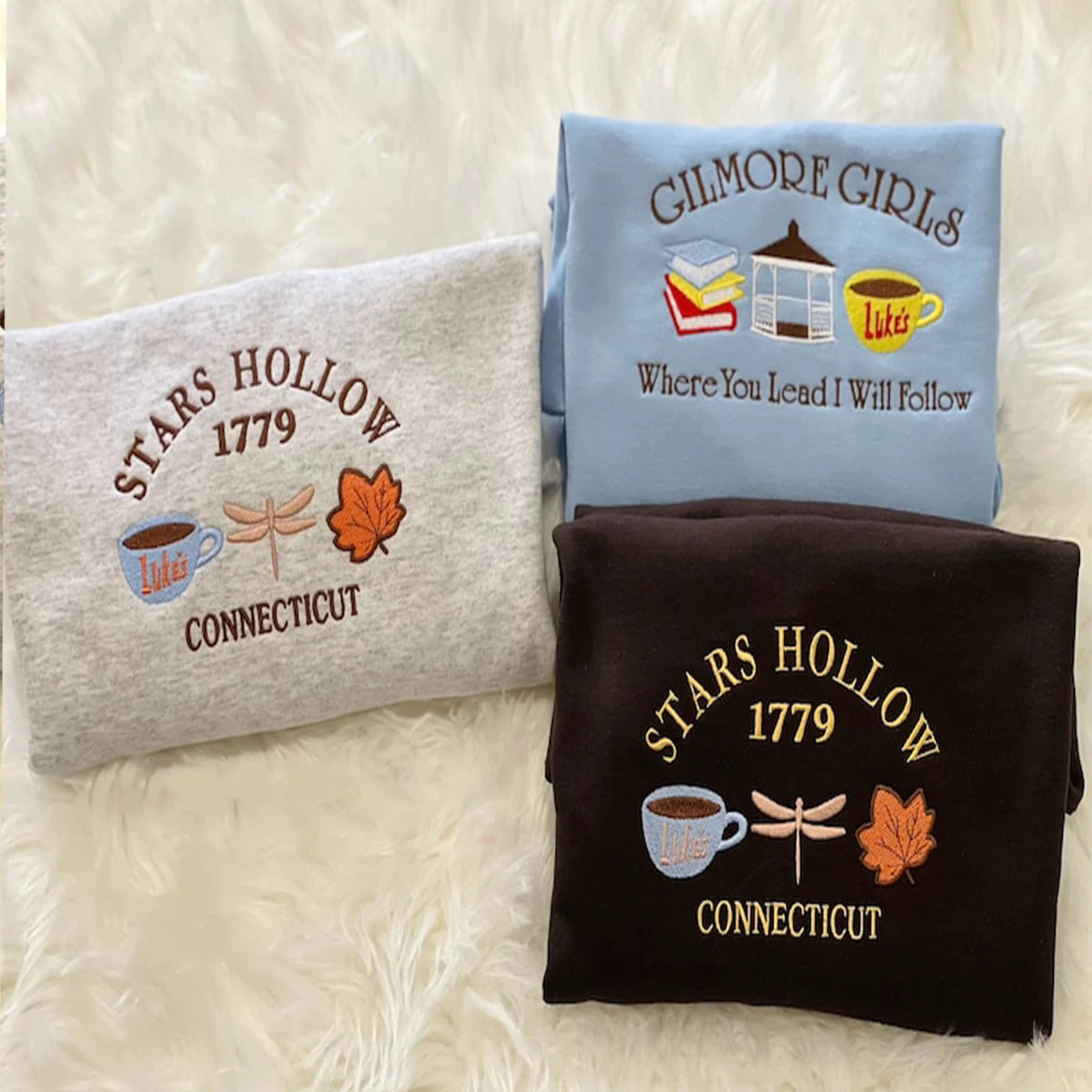 Three sweatshirts with 'Stars Hollow 1779' and 'Gilmore Girls' designs on a textured white background.