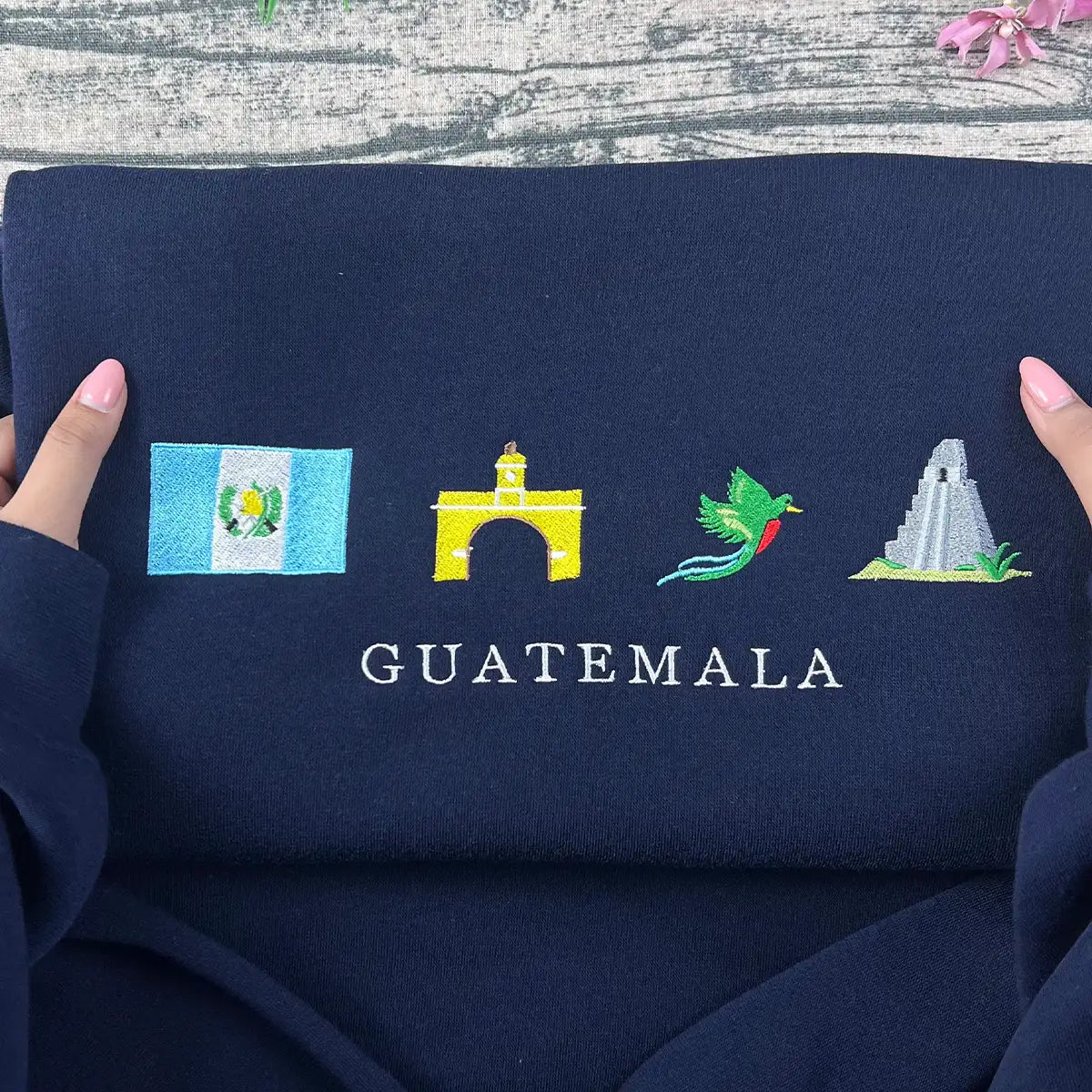 Navy blue fabric with embroidered designs of a flag, arch, bird, and pyramid with 'GUATEMALA' text.