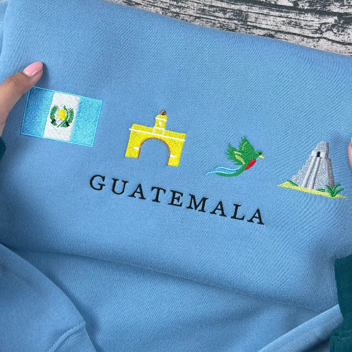 Blue fabric with embroidered designs and 'GUATEMALA' text on a wooden surface