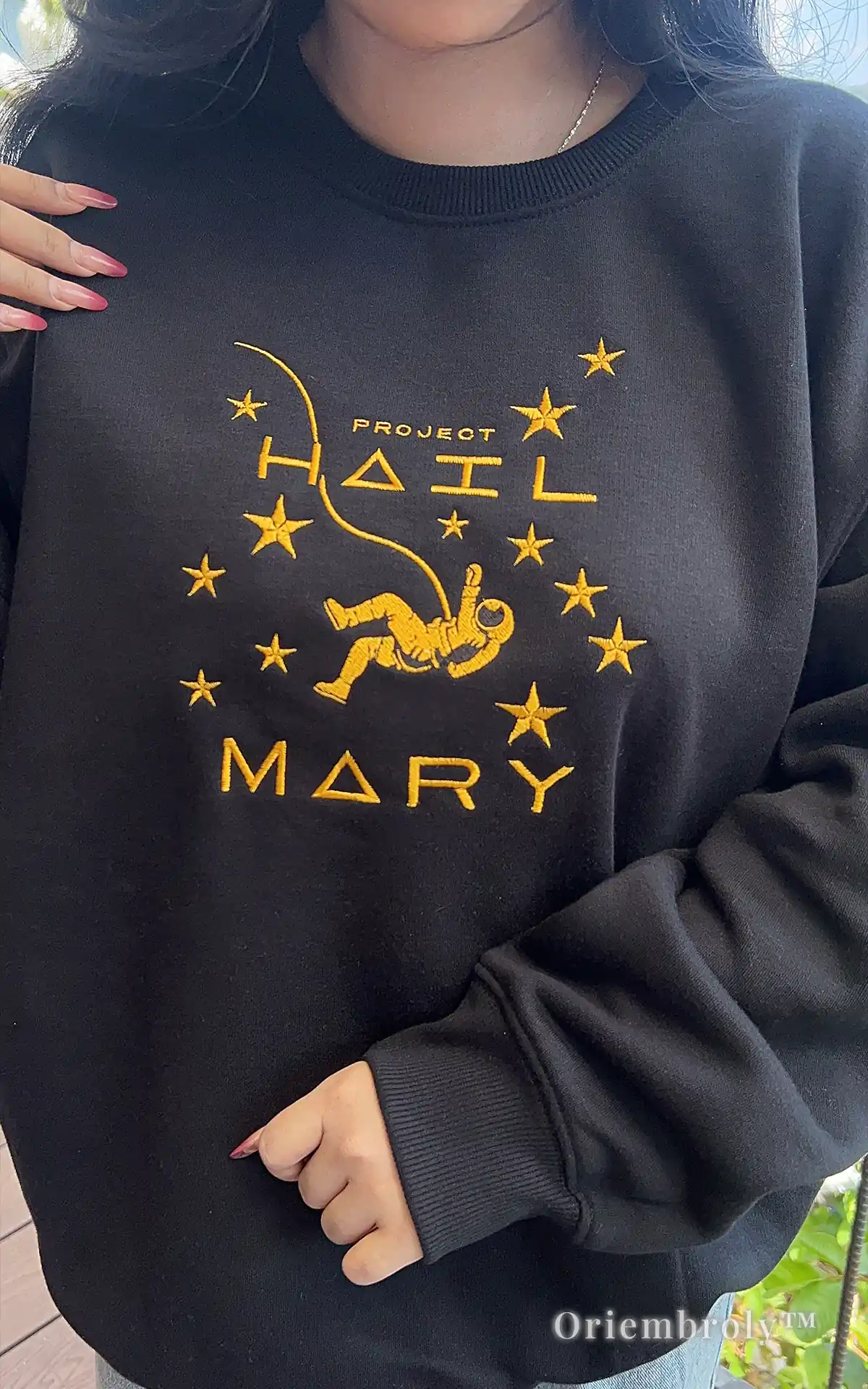 Close-up of a heavyweight black crewneck with premium yellow satin-stitched astronaut embroidery. Durable, high-quality thread work designed for long-lasting wear and comfort