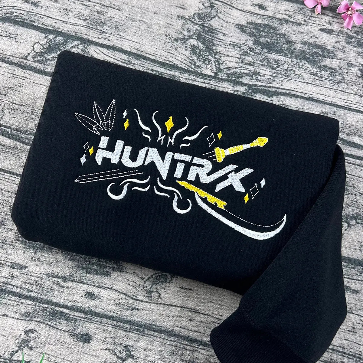 Black t-shirt with 'HUNTRK' logo on a wooden surface