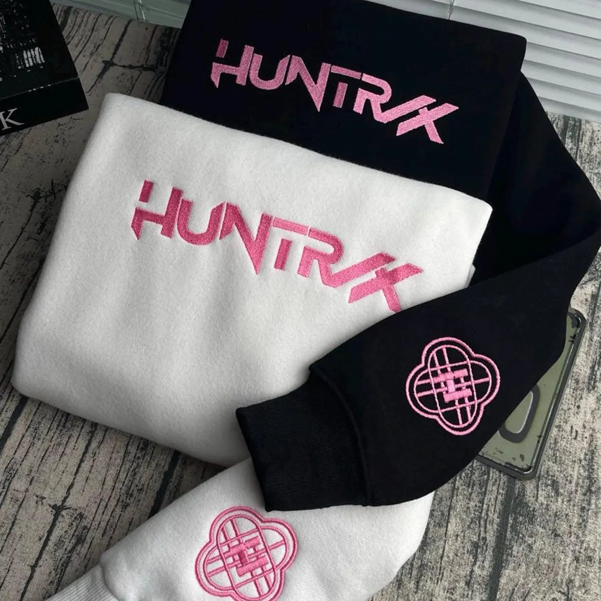 Black, white, and pink 'HUNTRX' branded items on a wooden surface