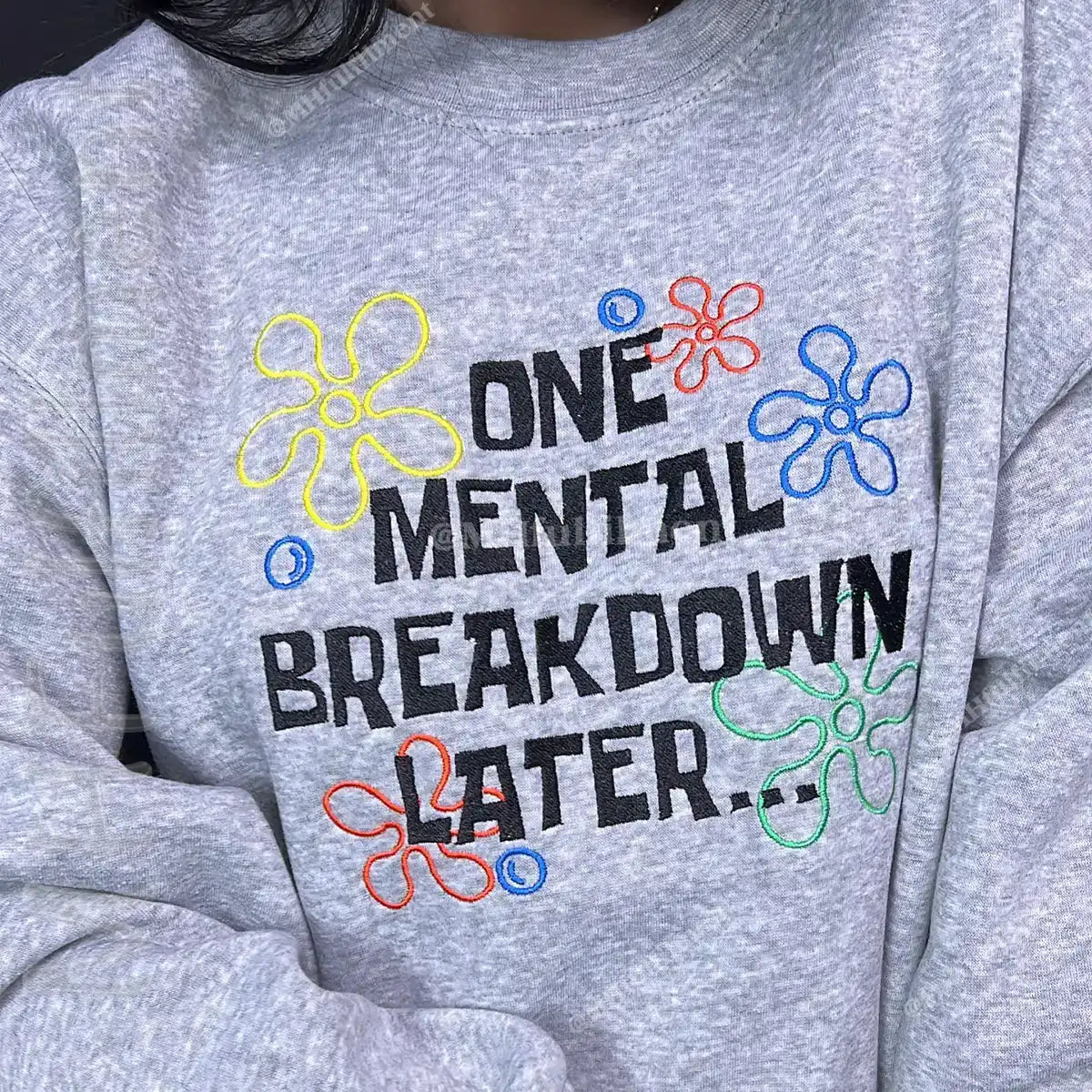 Gray sweatshirt with colorful text and flower designs on a gray background