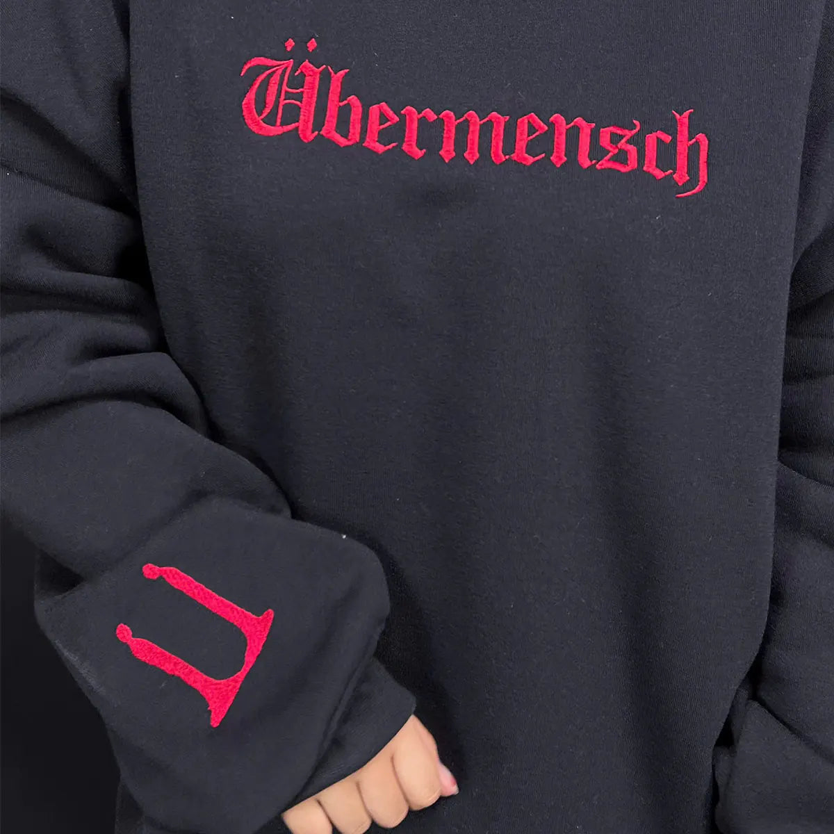 Black hoodie with red 'Ußermensch' text on a dark background