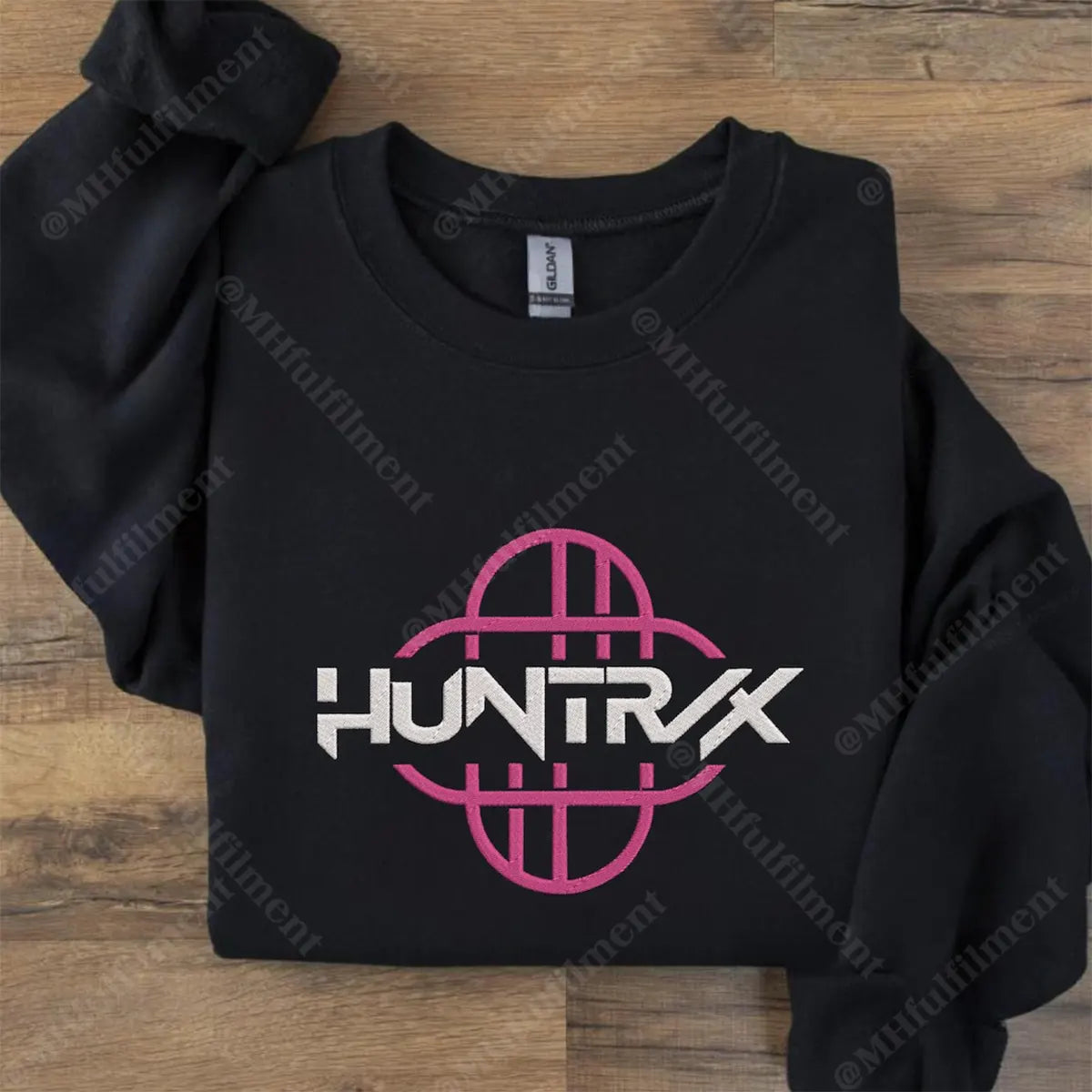 Black hoodie with pink and white logo on a wooden surface