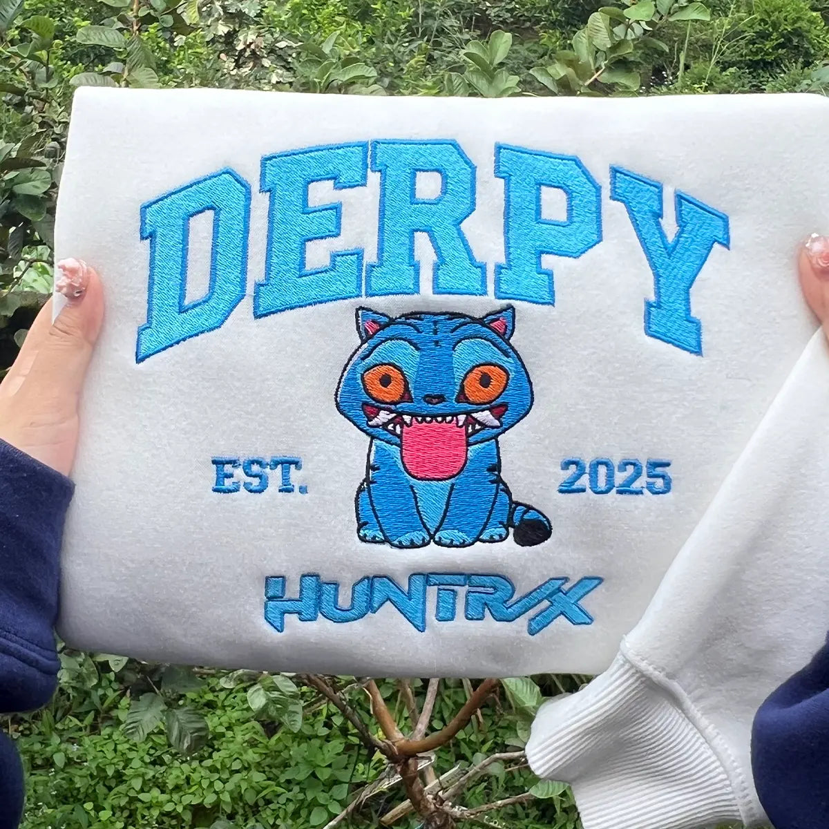 White pouch with blue text and cartoon character held by a person outdoors.