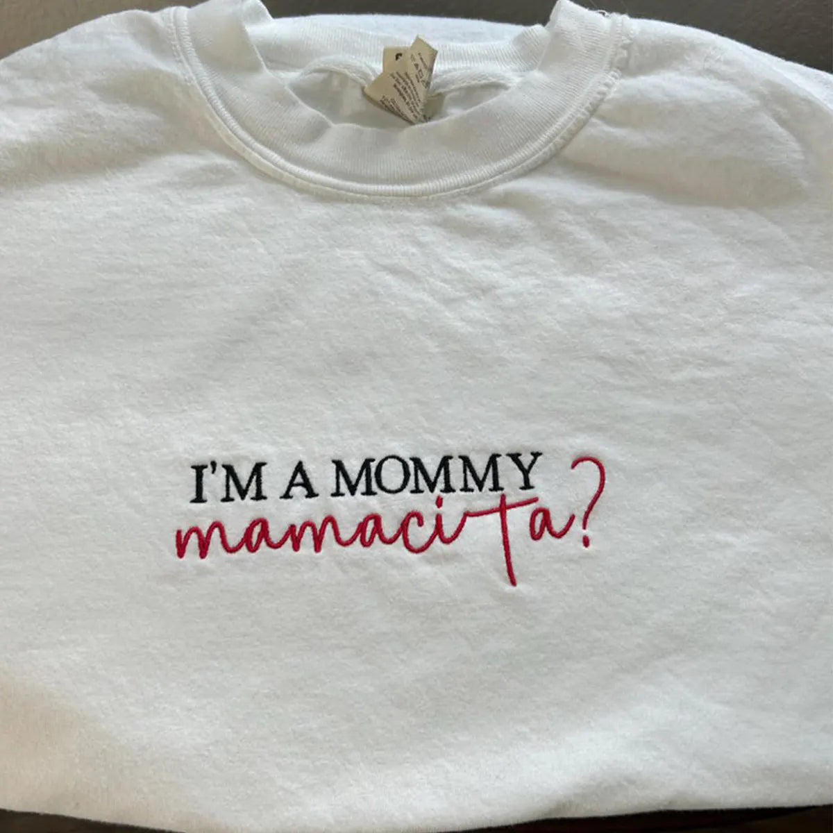 White sweatshirt with text 'I'm a mommy mamacita?' on a plain background