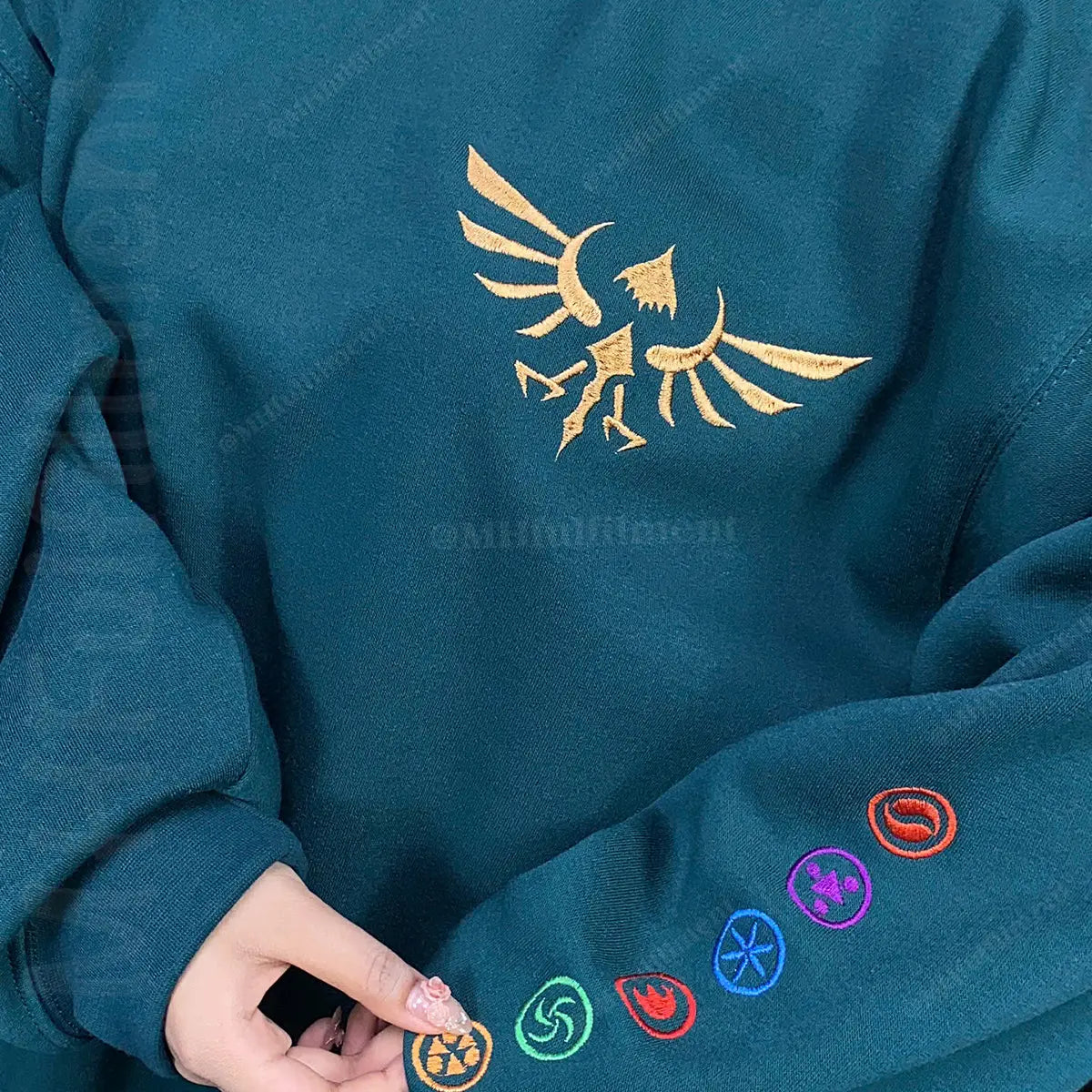 Teal sweatshirt with gold emblem and colorful symbols on a dark background