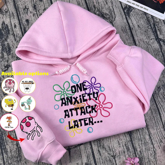 Pink hoodie with colorful text design on a wooden surface