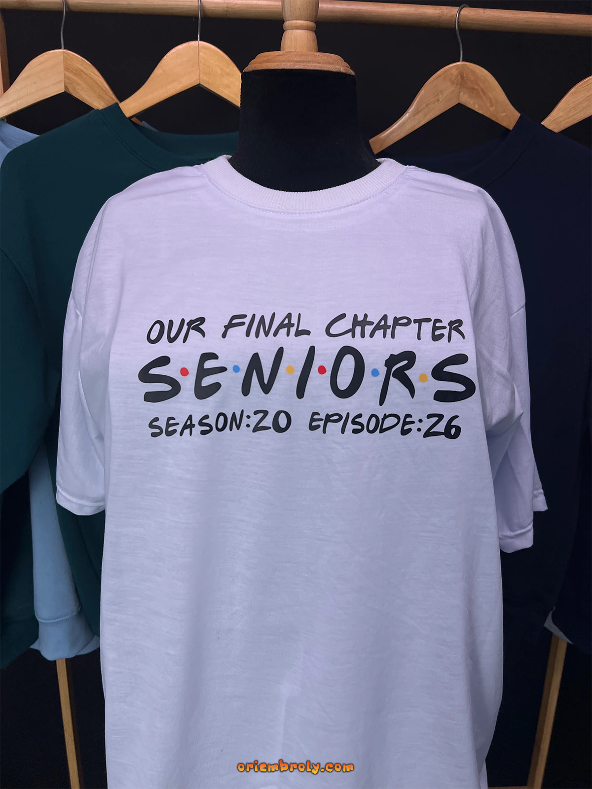 White t-shirt with 'Our Final Chapter Seniors' text on a mannequin against a dark background.