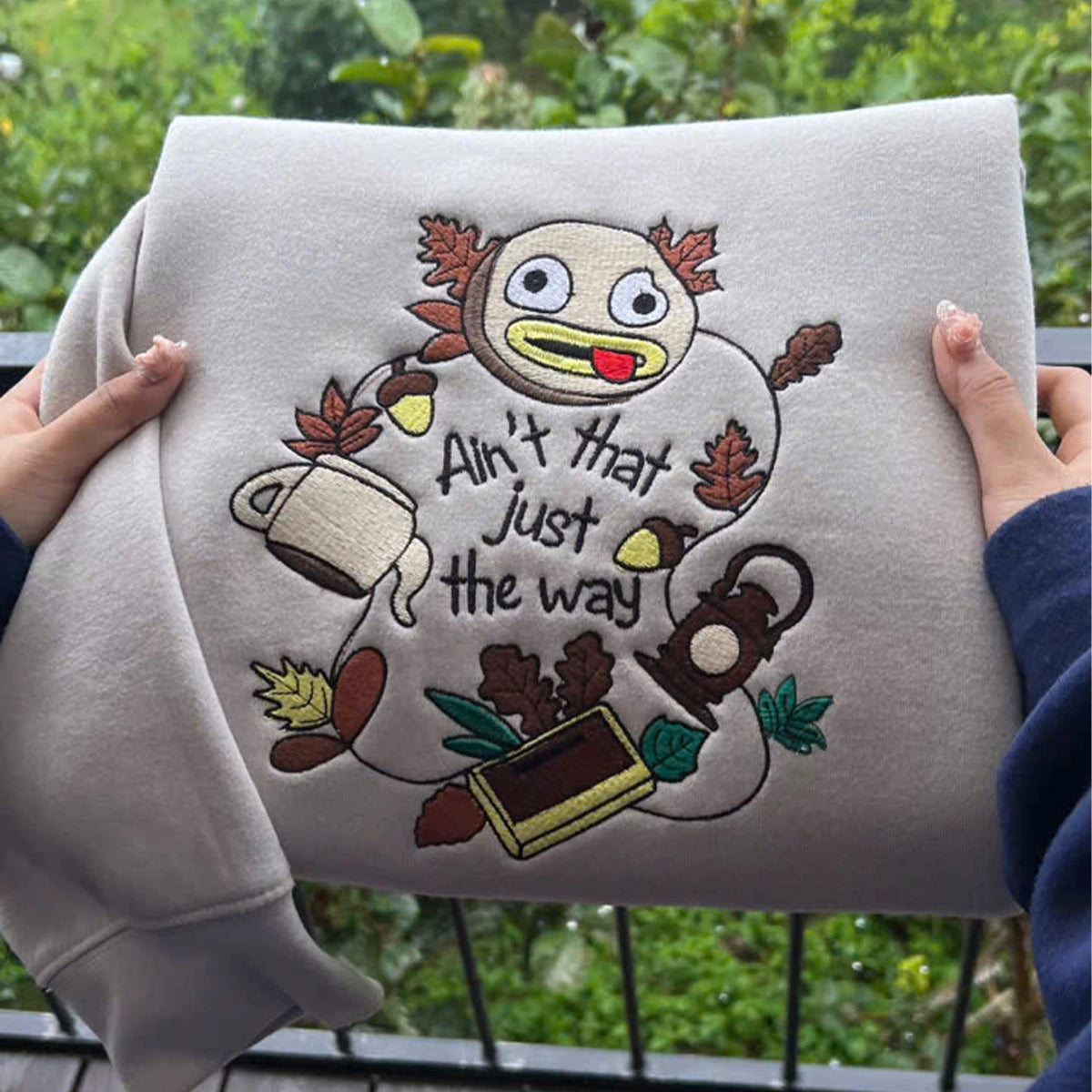 Embroidered design on a gray sweatshirt with cartoon character and text.
