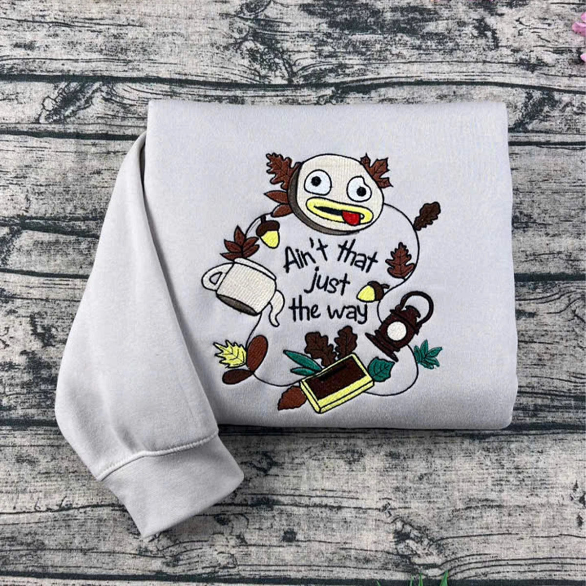 White sweatshirt with cartoon character and text on a wooden surface