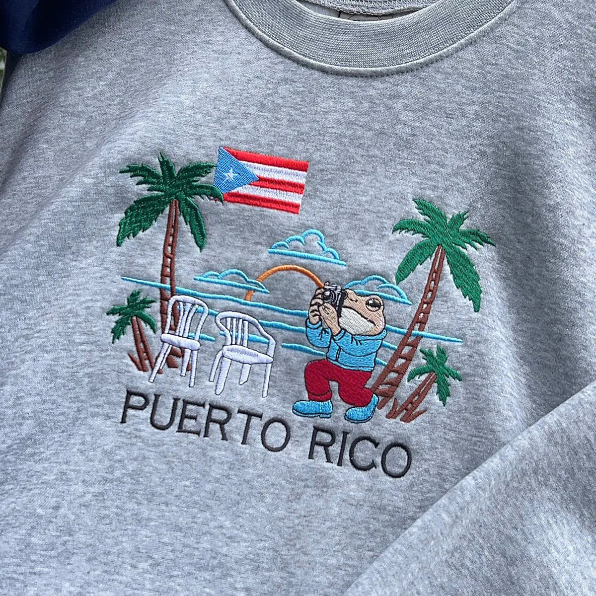 Gray sweatshirt with a Puerto Rico-themed design featuring a bear, palm trees, and a flag.