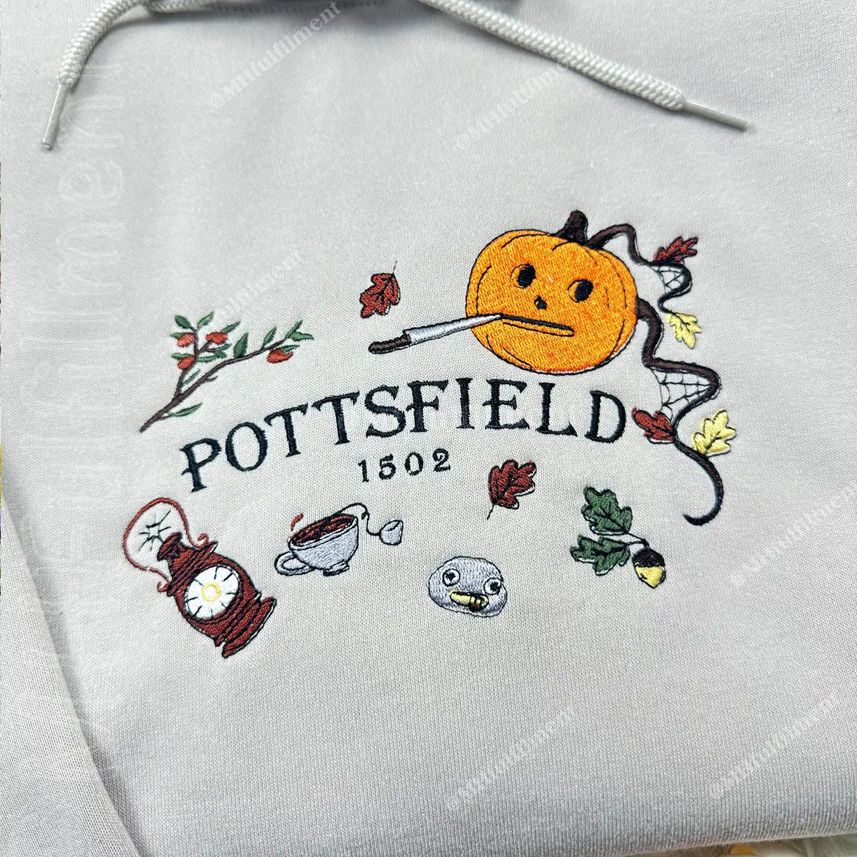 Embroidered design on a gray hoodie with 'Pottsfield' and various symbols.