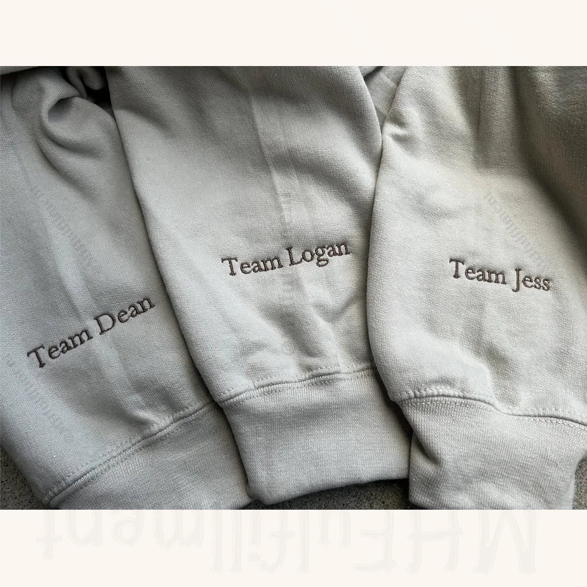 Three gray sweatpants with embroidered names on a neutral background