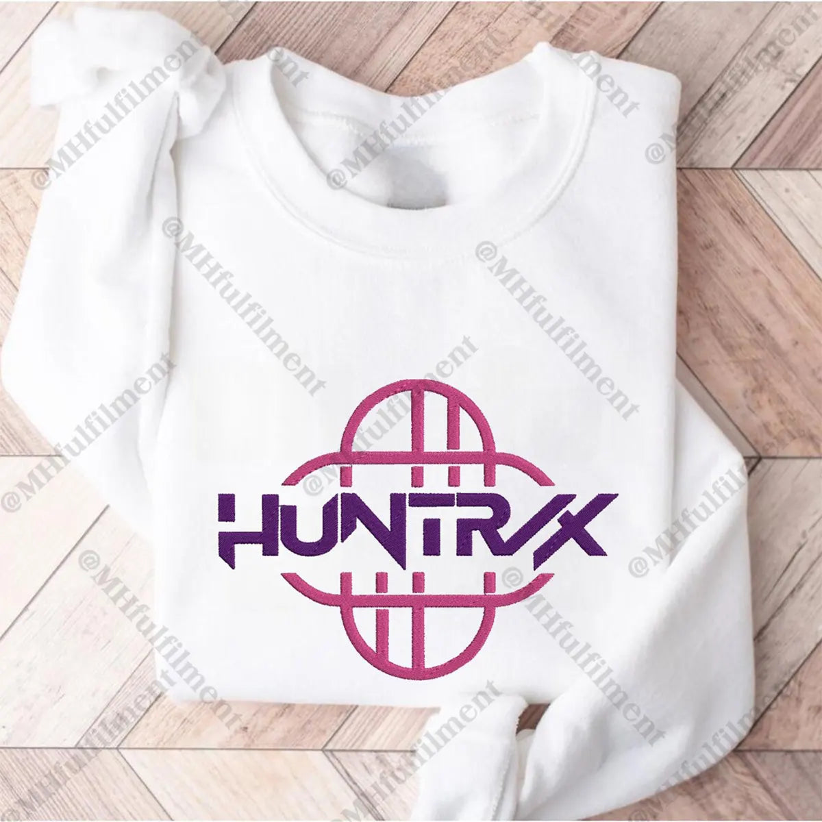 Folded white sweatshirt with 'HUNTRX' logo on a wooden surface