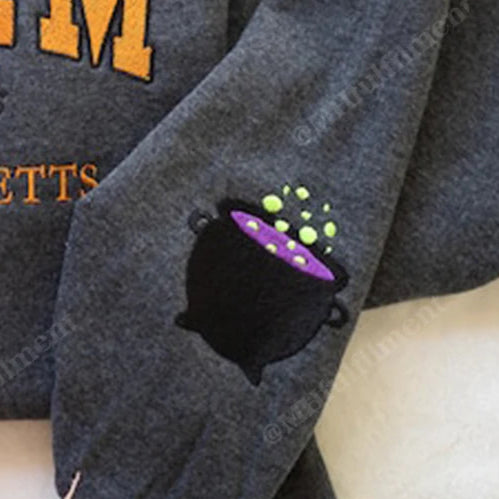 Gray sweatshirt with 'Salem, Massachusetts' text and witch hat design on a white surface.