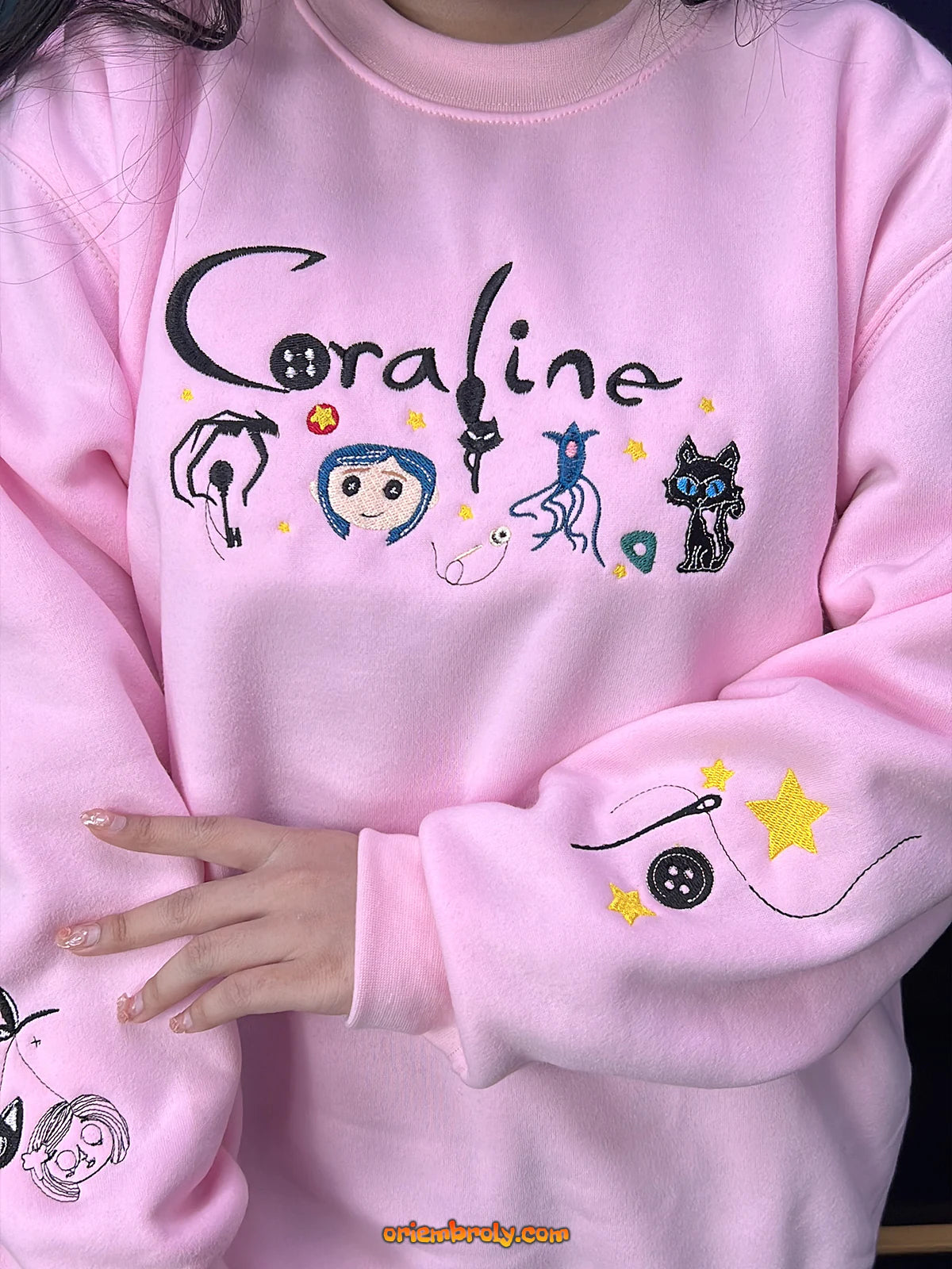Pink sweatshirt with 'Coraline' design featuring characters and text.