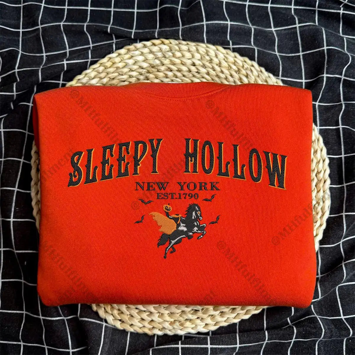 Red blanket with 'Sleepy Hollow New York' text and horse graphic on a woven basket against a black checkered background.