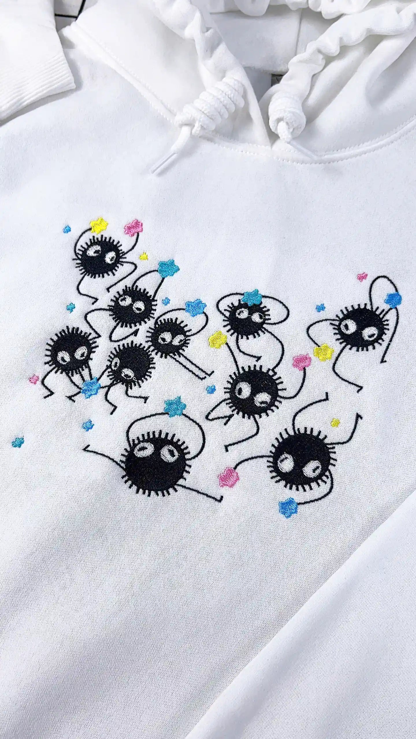 White hoodie with black embroidered designs on a white background