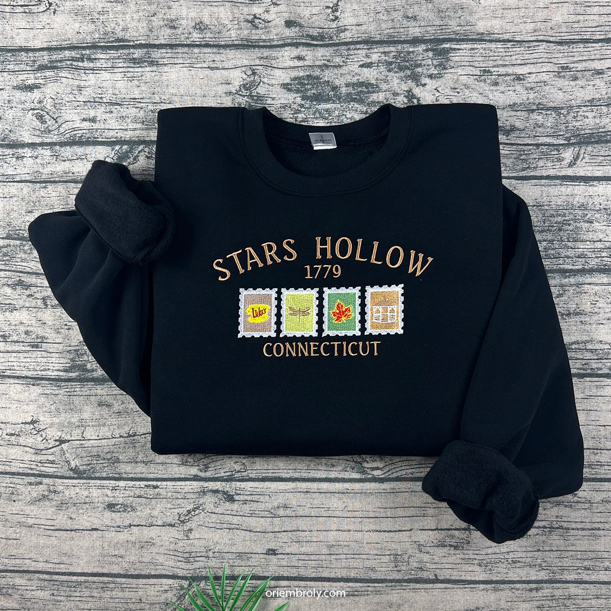 Black sweatshirt with 'Stars Hollow 1779 Connecticut' text and graphics on a wooden surface
