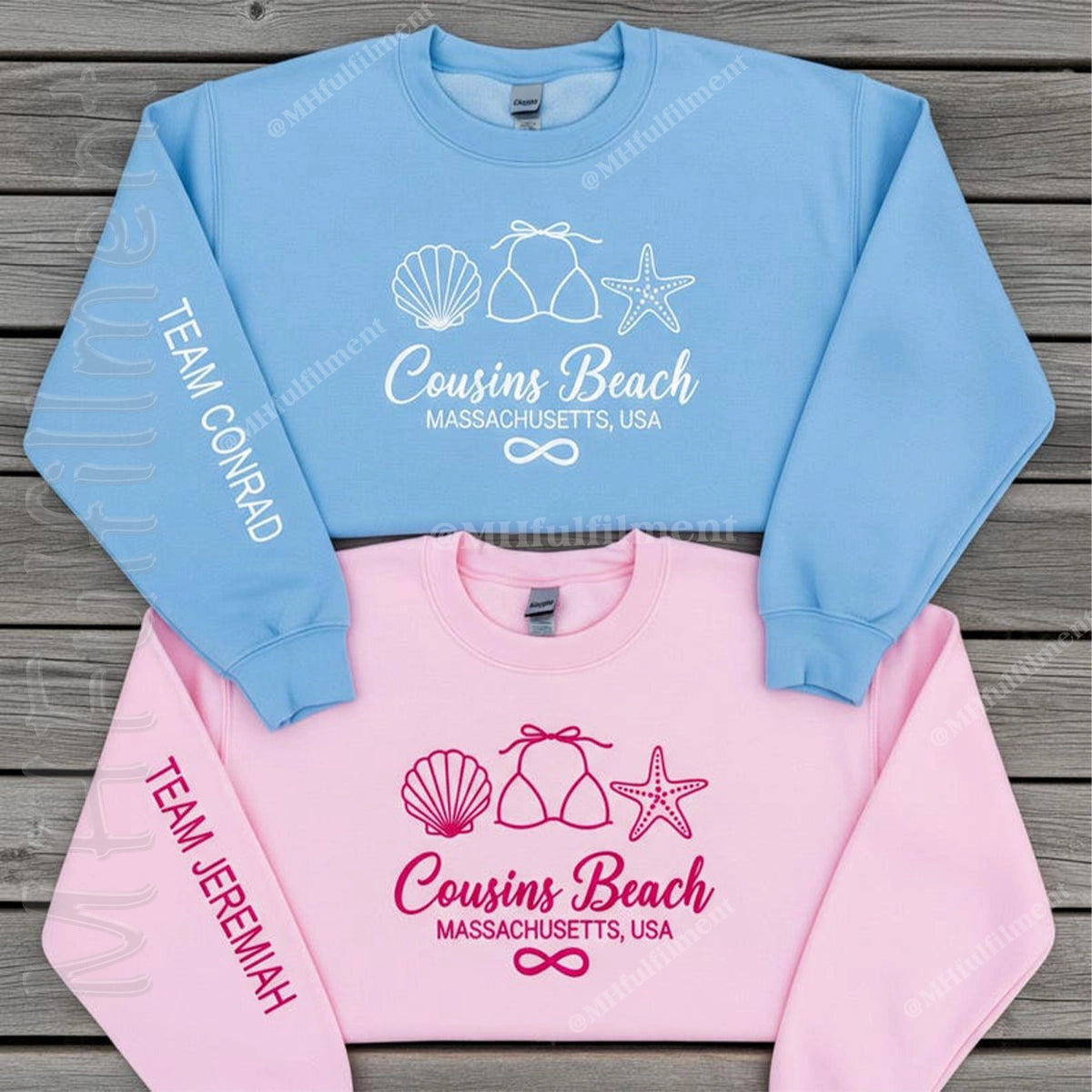 Two sweatshirts, one blue and one pink, with 'Cousins Beach' text and graphics on a wooden surface.