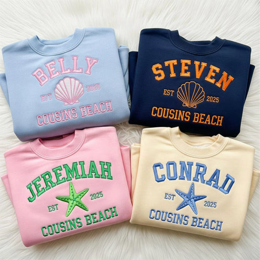 Four folded sweatshirts with personalized names and 'Cousins Beach' text on a light wooden surface.