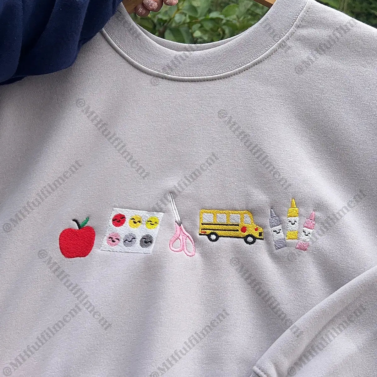 Gray sweatshirt with various embroidered designs including an apple, school bus, and other elements.