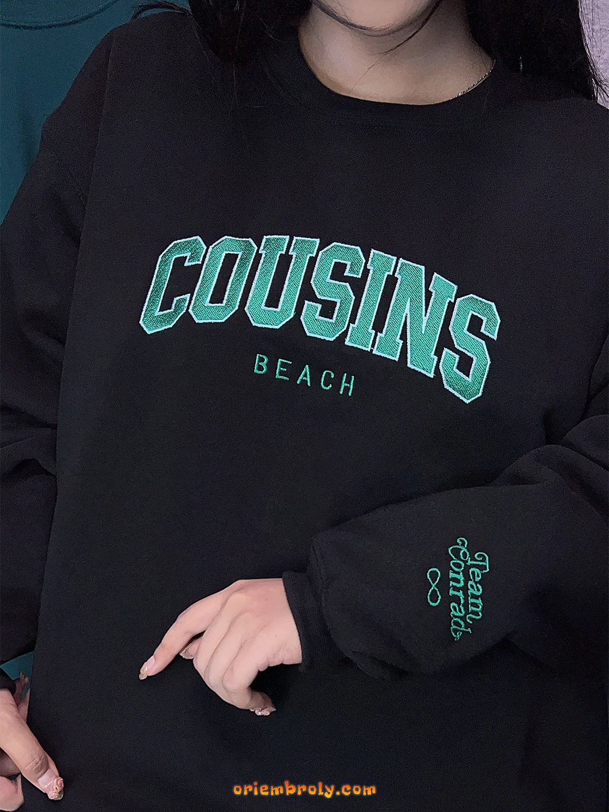 Black sweatshirt with 'COUSINS BEACH' text in green on a person wearing headphones.