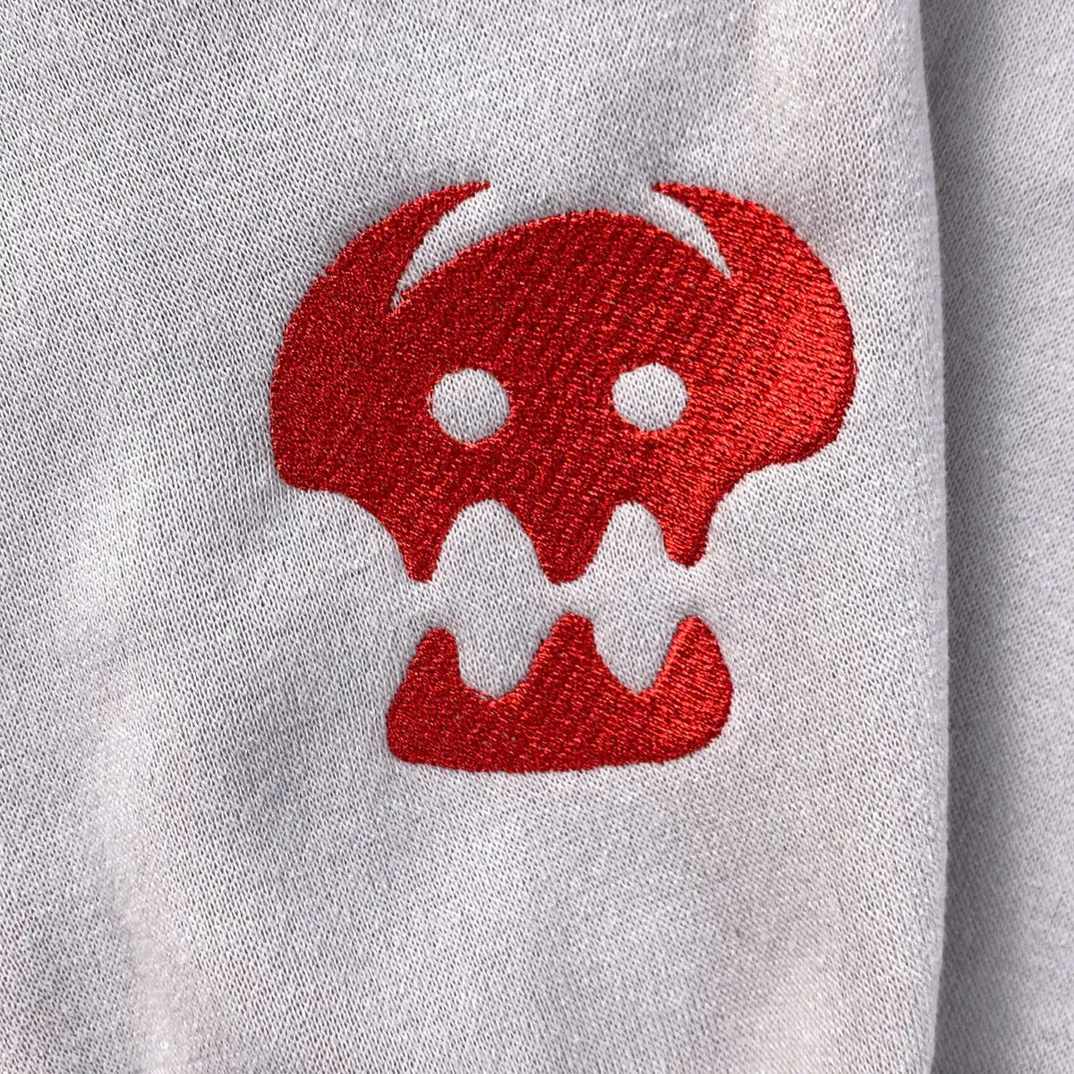Red embroidered skull design on a gray sweatshirt