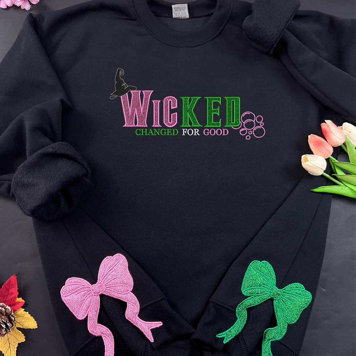 Black hoodie with 'Wicked Changed for Good' text and decorative bows on a dark background.