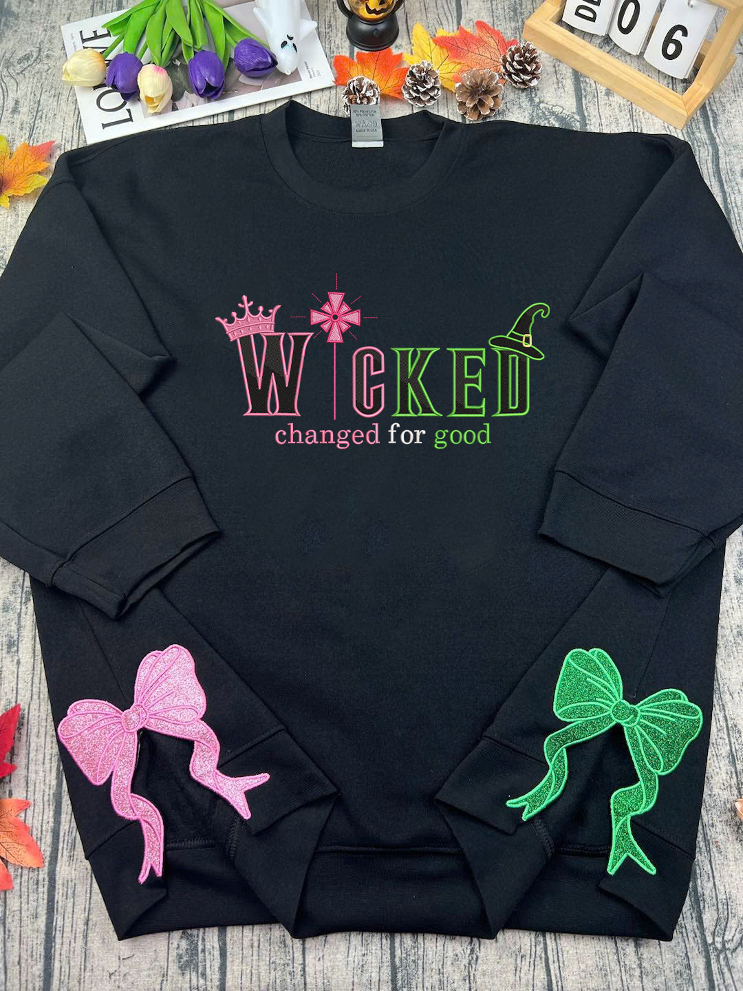 Black sweatshirt with colorful text and bows on a wooden surface