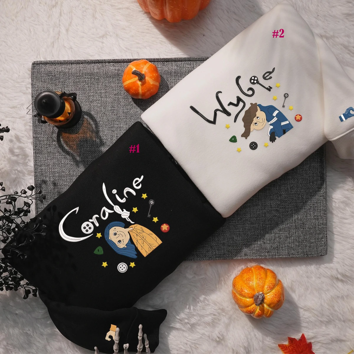 Two socks with embroidered designs and text on a textured surface with pumpkins and a bottle.