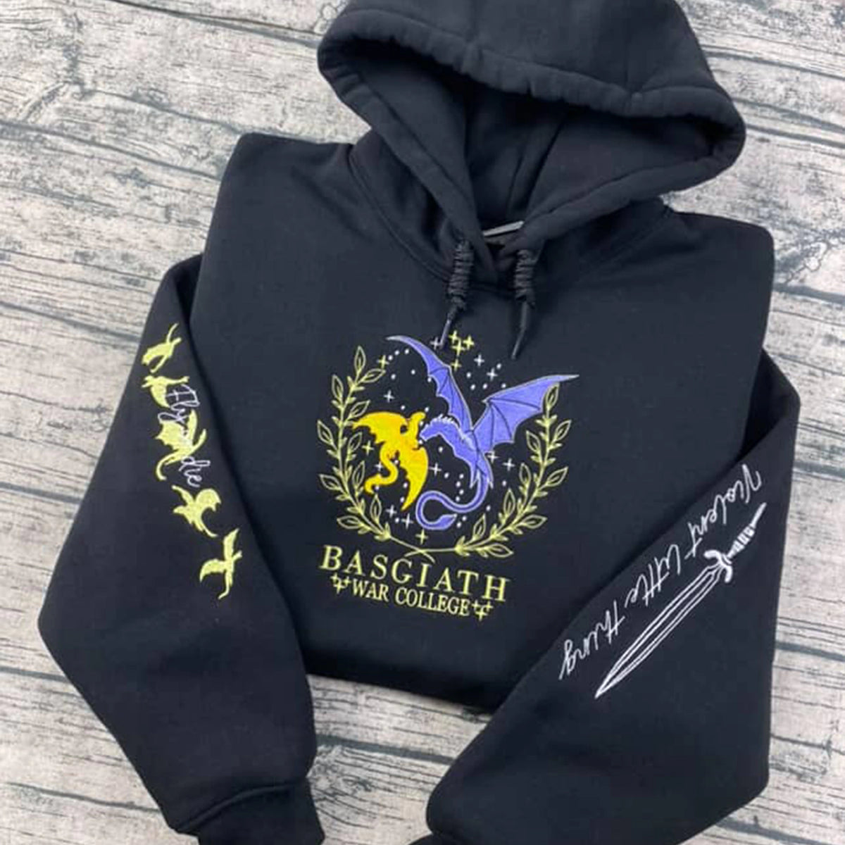 Black hoodie with dragon design and text on a wooden surface