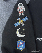Black jacket with embroidered space-themed patches including an astronaut, satellite, moon, and shield design.