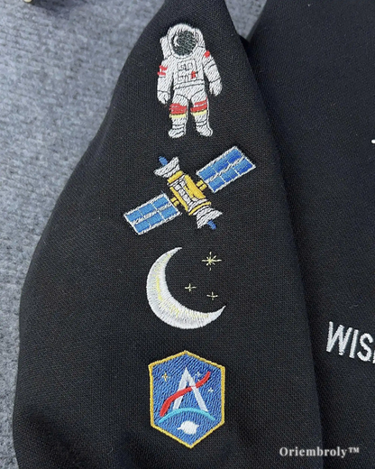 Black jacket with embroidered space-themed patches including an astronaut, satellite, moon, and shield design.